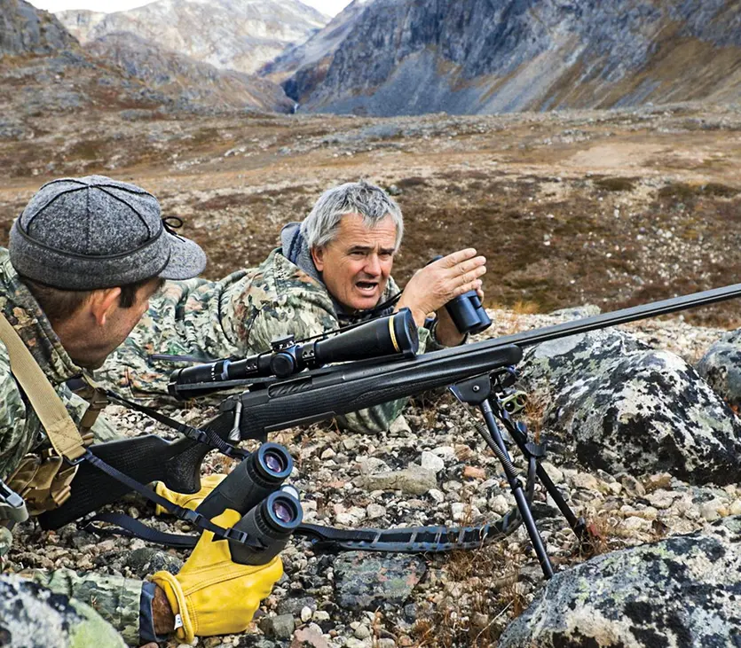 Hunters in shooting position on rock outcrop.